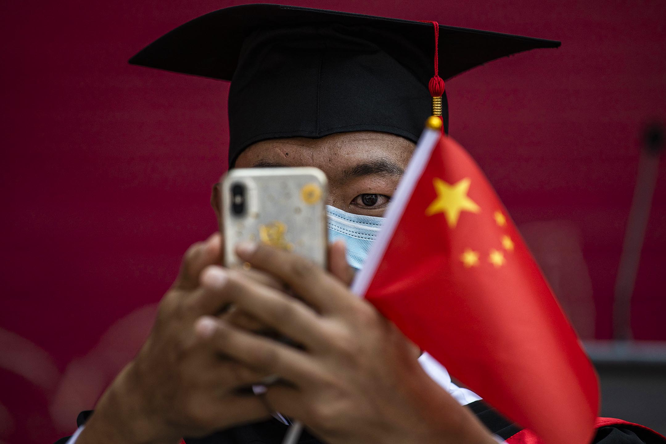2020年6月30日在中國北京,中國人民大學的學生拿著一面國旗參加畢業典禮。