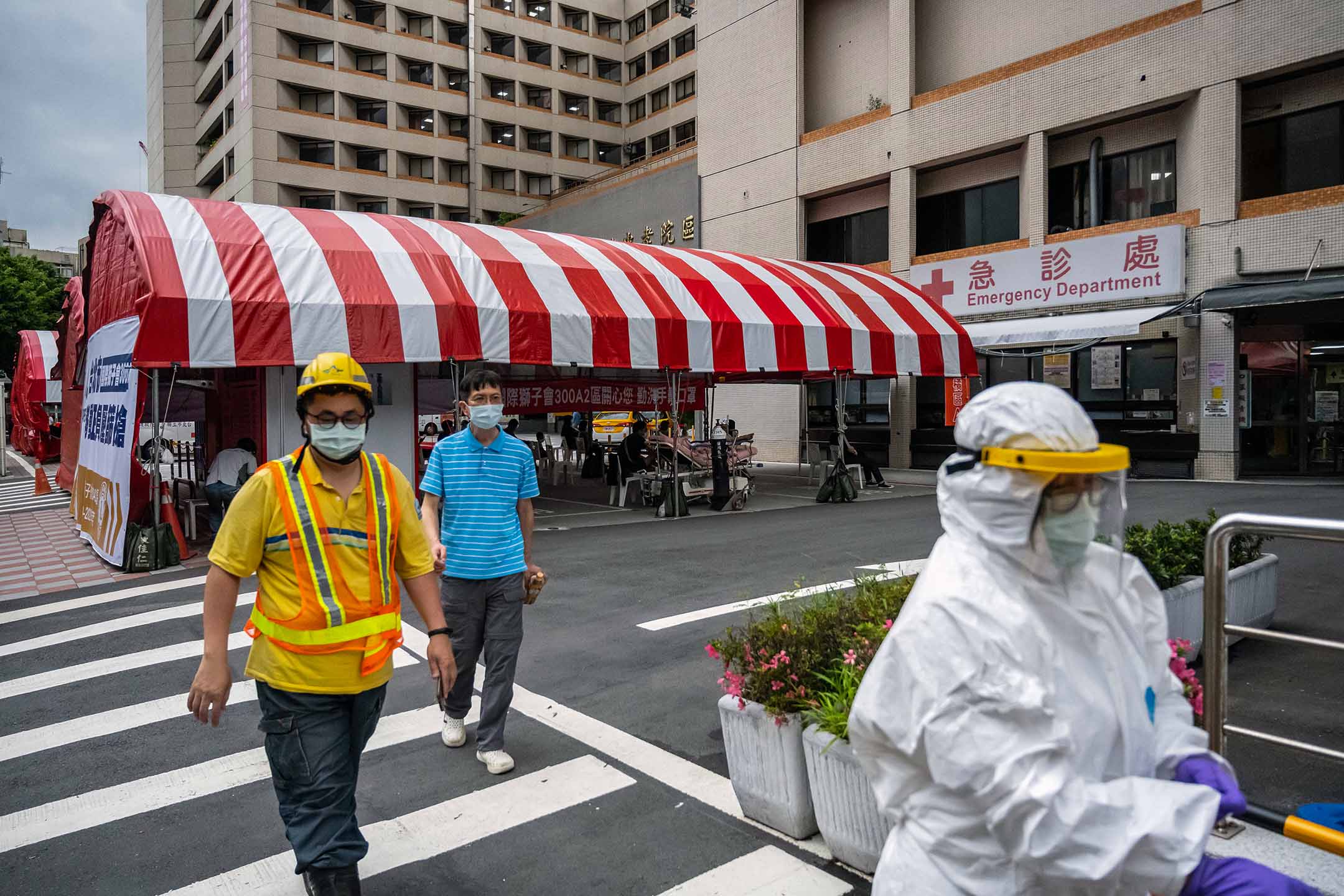 2021年6月3日台湾台北,戴着防护口罩的行人走过一家医院外搭建的帐篷。