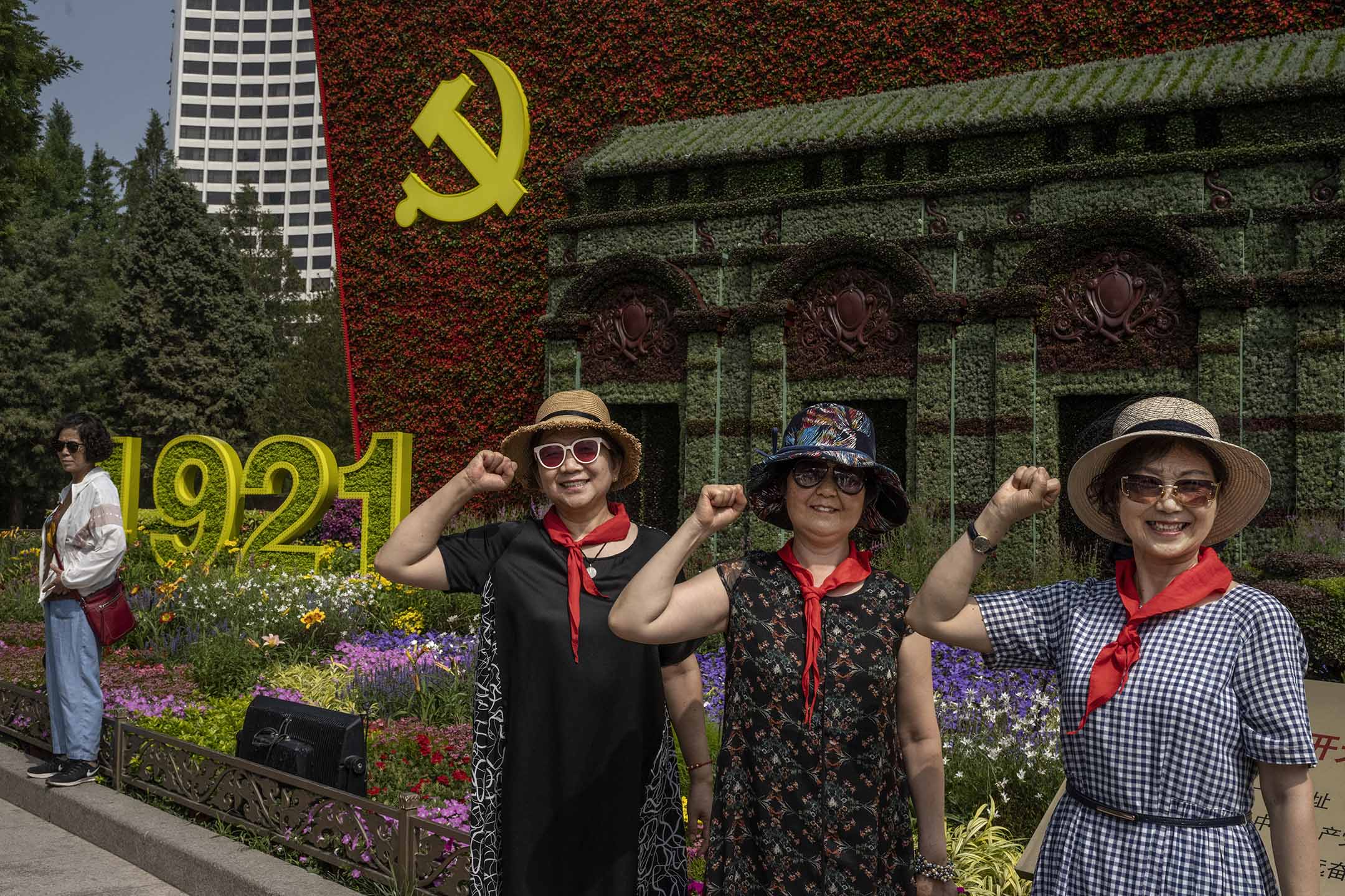 2021年6月27日中国北京,街道上设置的花展上,妇女们在中国共产党的大型标志前拍照。