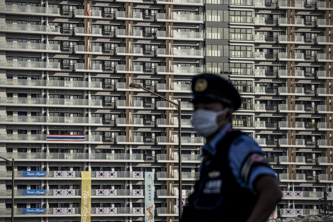 2021年7月19日,东京一名警察在东京奥运会运动员村的住宿楼旁站岗。