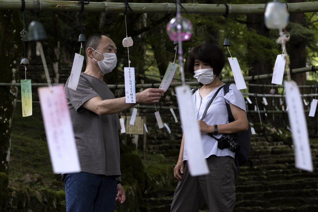 2021年7月13日,丹波一名戴著口罩的市民在青垣寺閲讀印有人們願望的風鈴紙條。