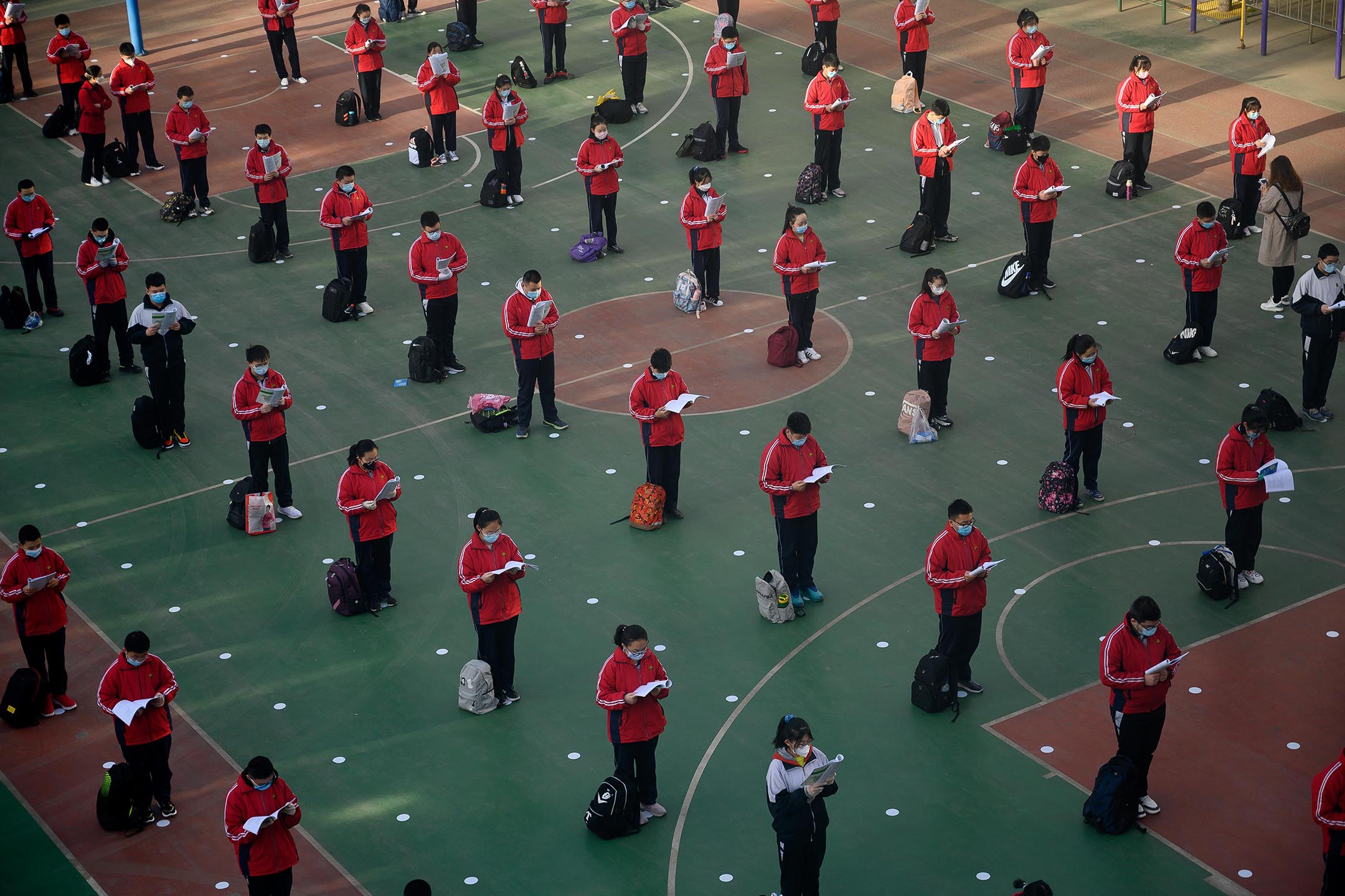 2020年4月25日中国太原,中学重新开放的第一天,戴着口罩的学生在操场上读书。
