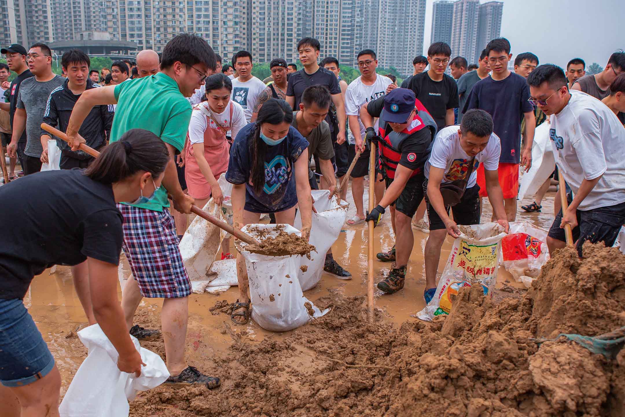 2021年7月23日中國新鄉,救援隊和居民使用沙袋建造圍堰,防止暴雨後的洪水。