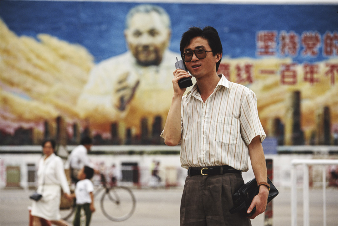 1993年,深圳一名男子正在使用手提電話,背後是鄧小平巨型室外宣傳畫。