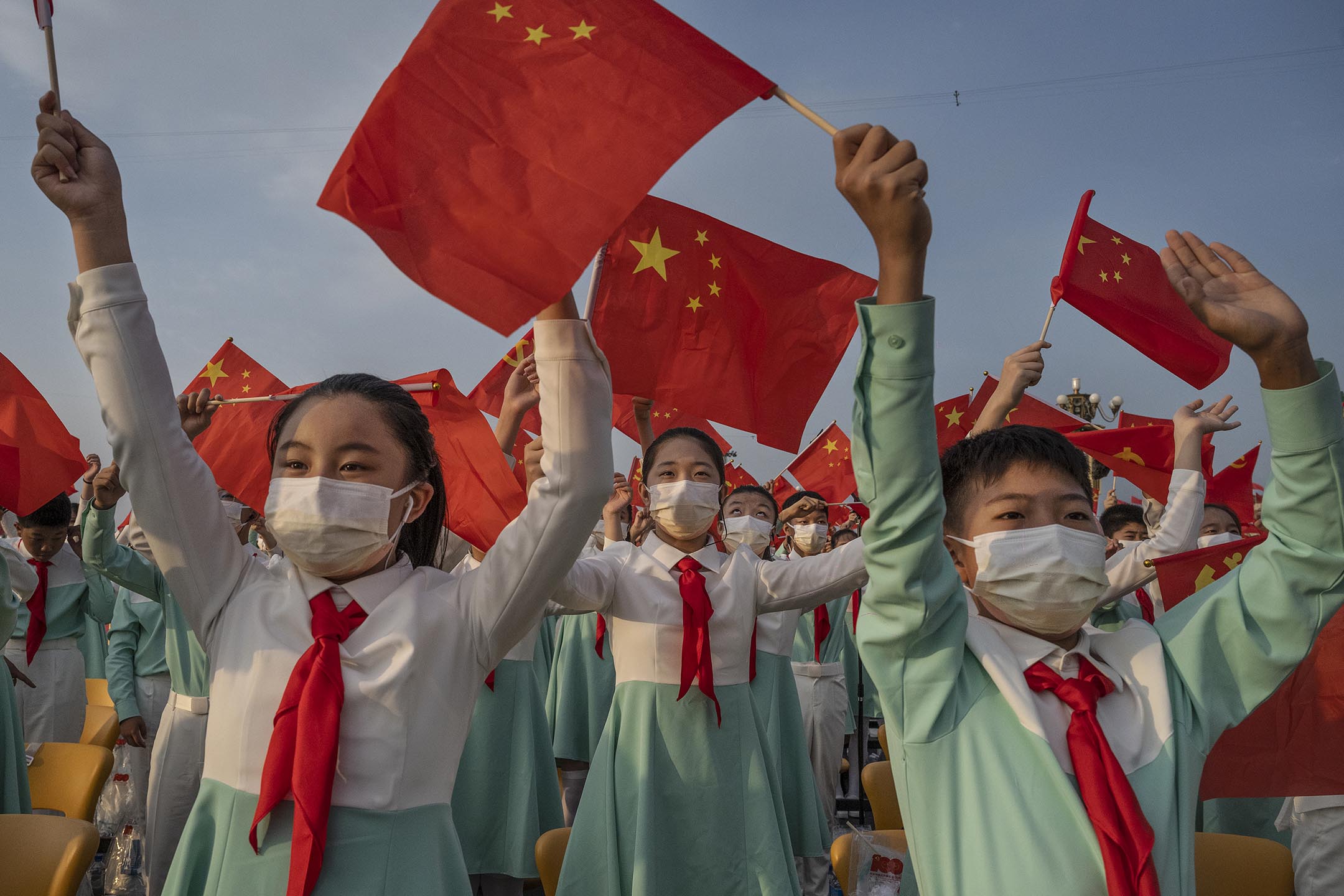 2021年7月1日中國北京,中國學生在天安門廣場舉行的慶祝共產黨成立 100 週年的儀式上揮舞黨旗和國旗。