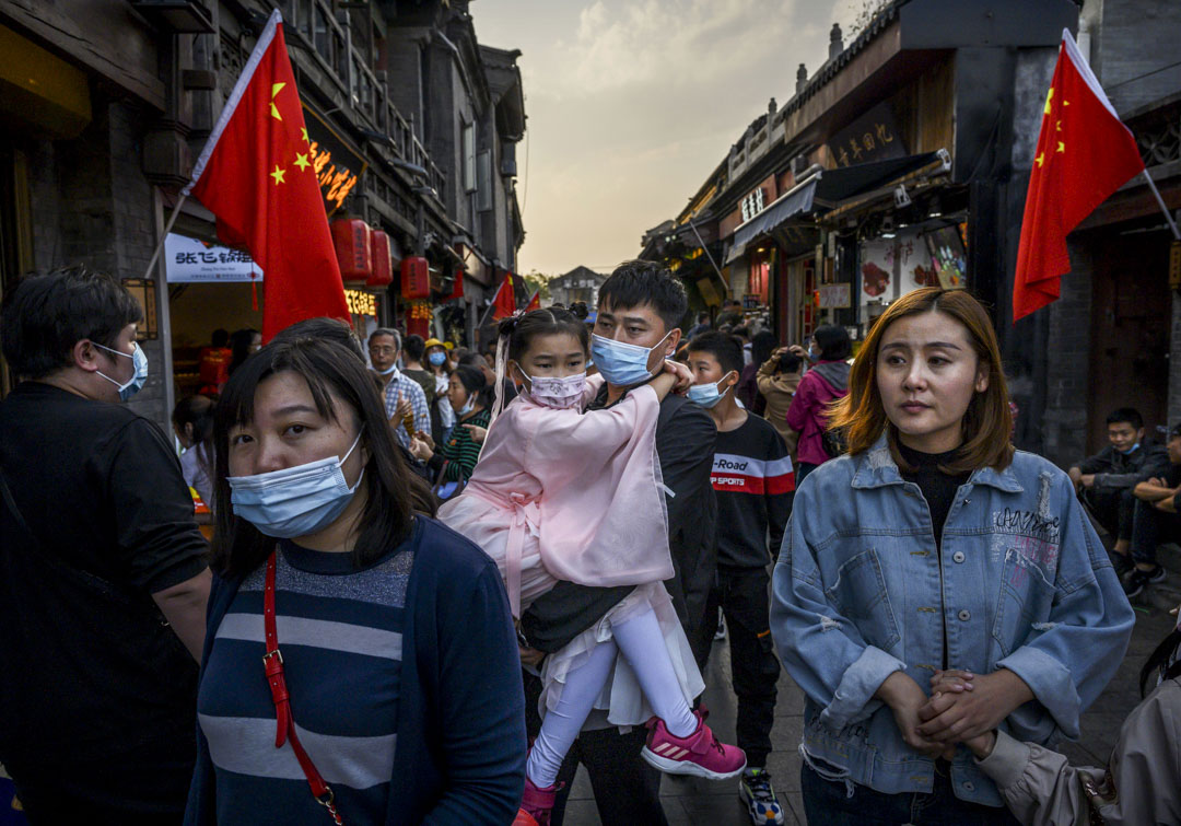 2020年10月3日,北京的黃金周假期,一名中國男子帶著身著傳統服裝的女兒在商業和旅遊區散步。