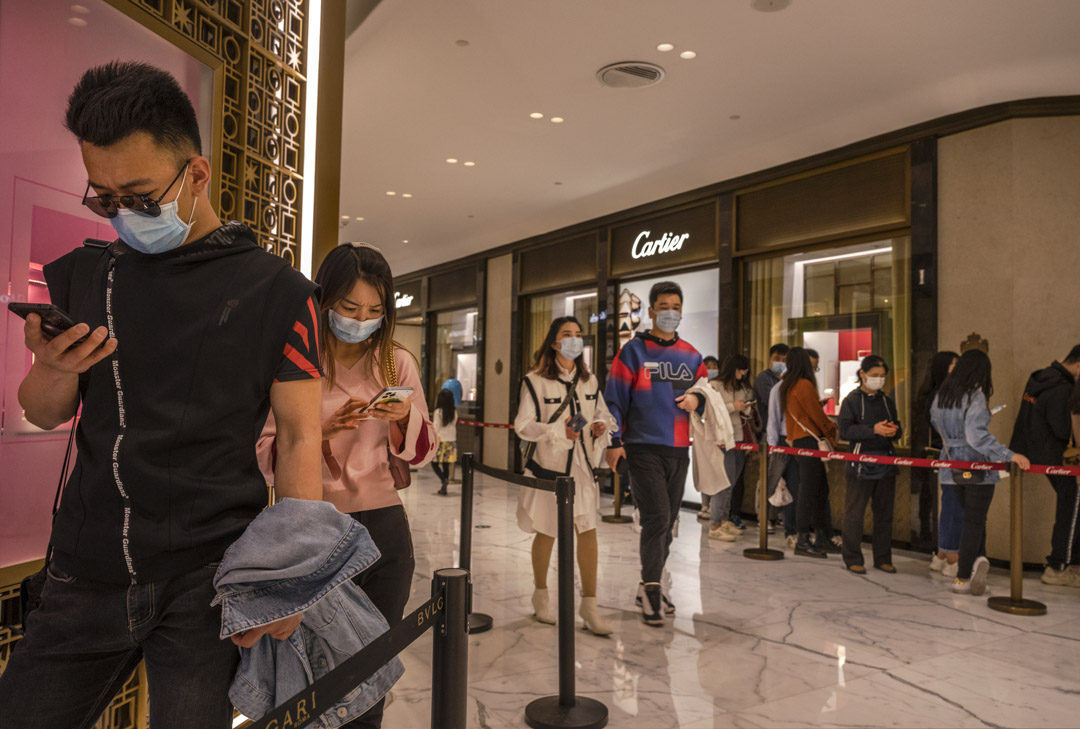 2021年4月18日,北京的年轻消费者在奢侈品店外等待进场时观看手机。