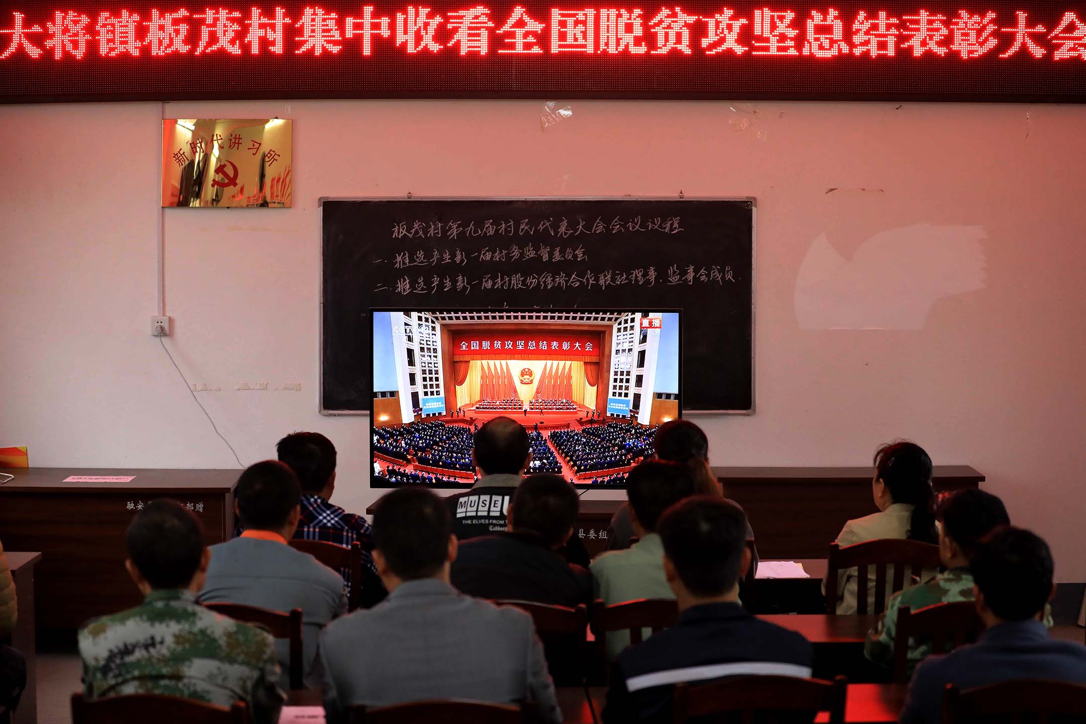 2021年2月25日中國柳州,中國共產黨成員觀看電視屏幕播放人民大會堂舉行的「全國脱貧攻堅總結表彰大會」。