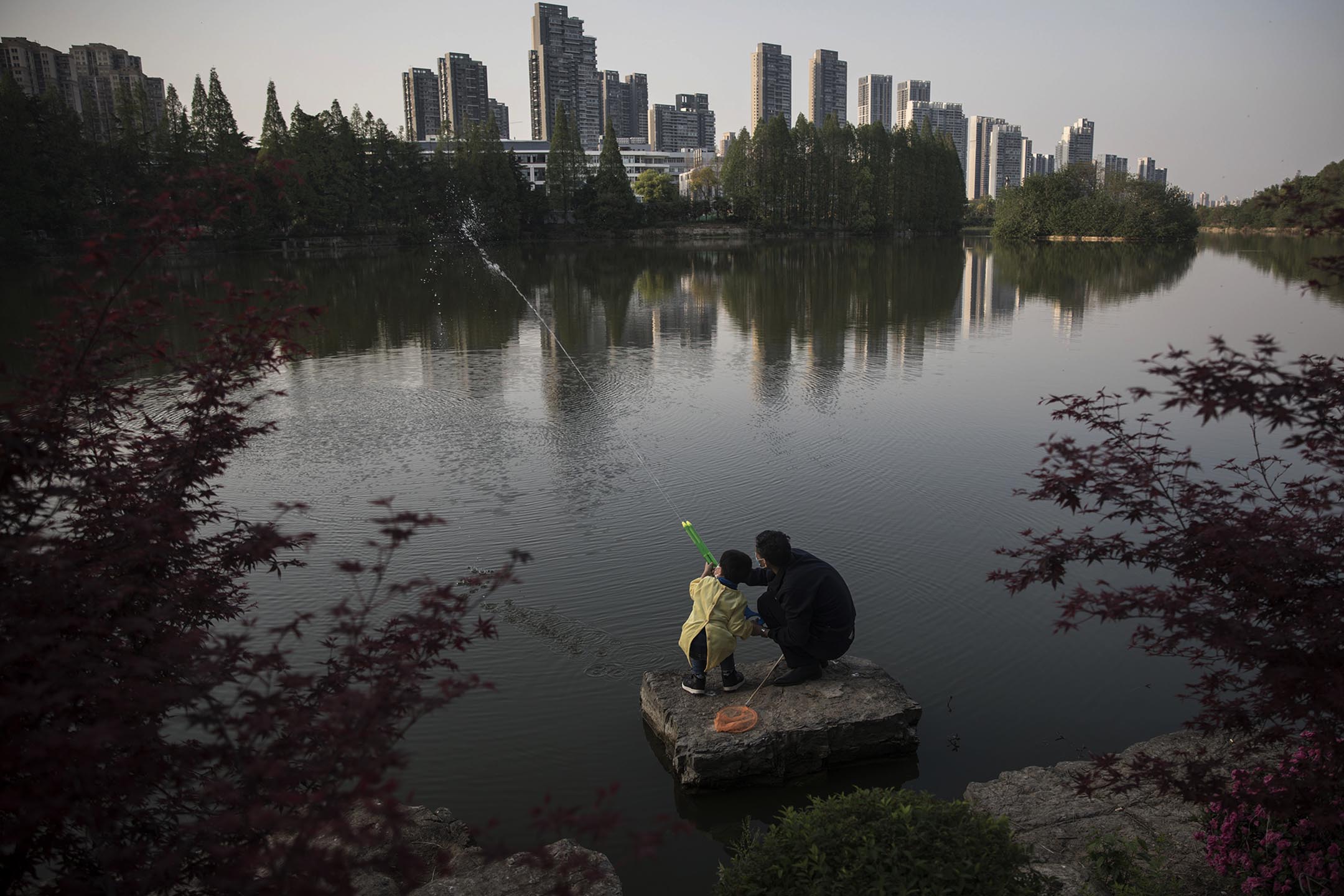 2020年4月9日中国武汉,一个男孩和他的爷爷在公园玩水枪。