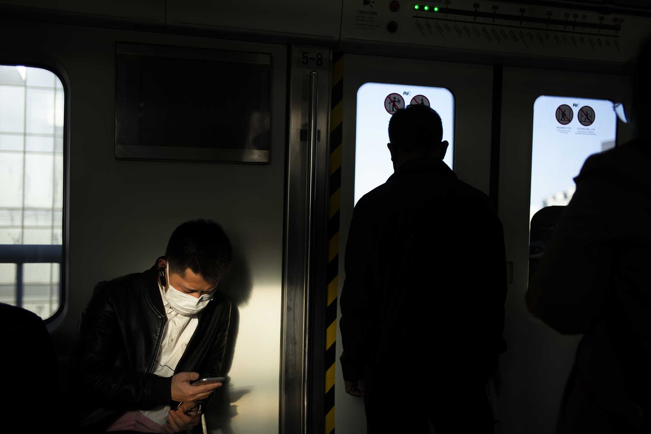 2020年4月2日中國北京,一名男子戴著口罩坐在地鐵上看手機。