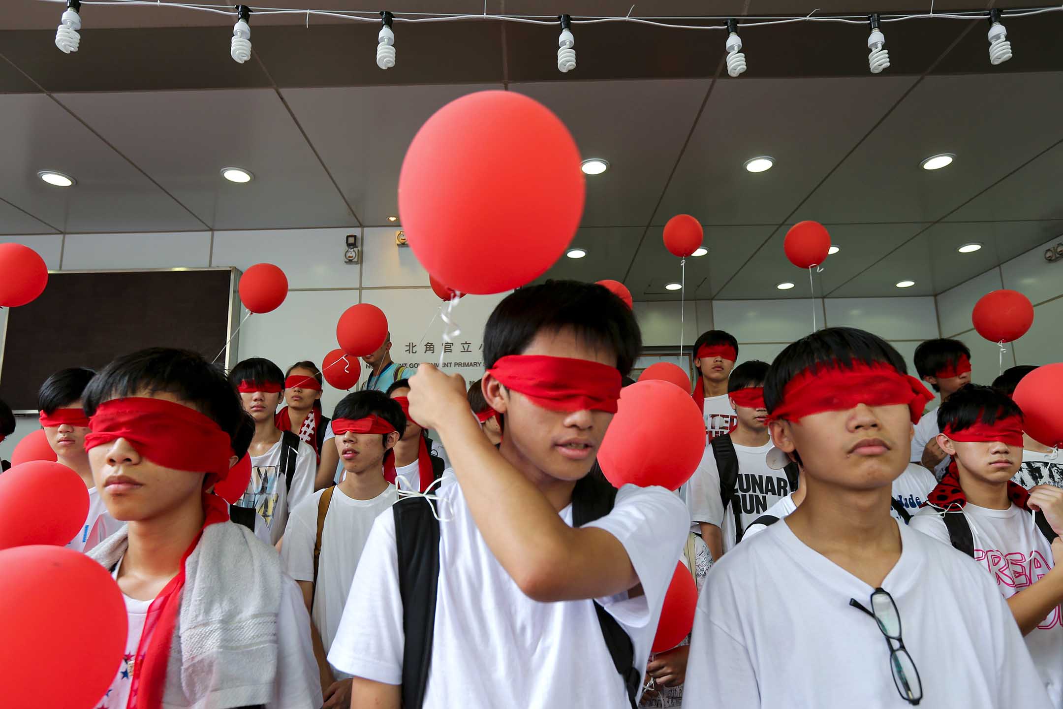 2012年8月28日,示威者在北角官立小學外戴著紅色眼罩拿著氣球,抗議國民教育。