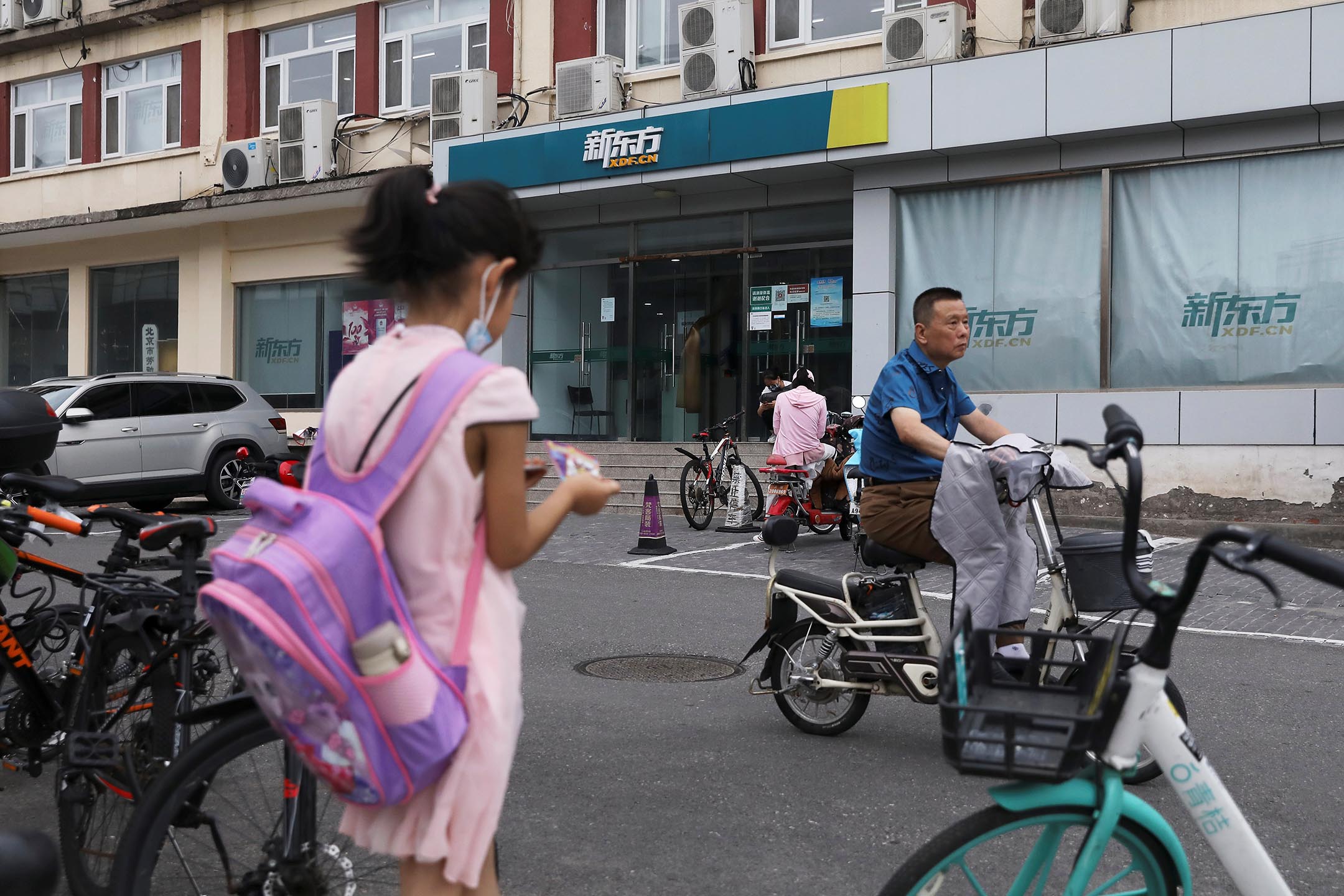 2021年7月26日中国北京,一名背著书包的女孩站在新东方教育科技集团的一家店附近。