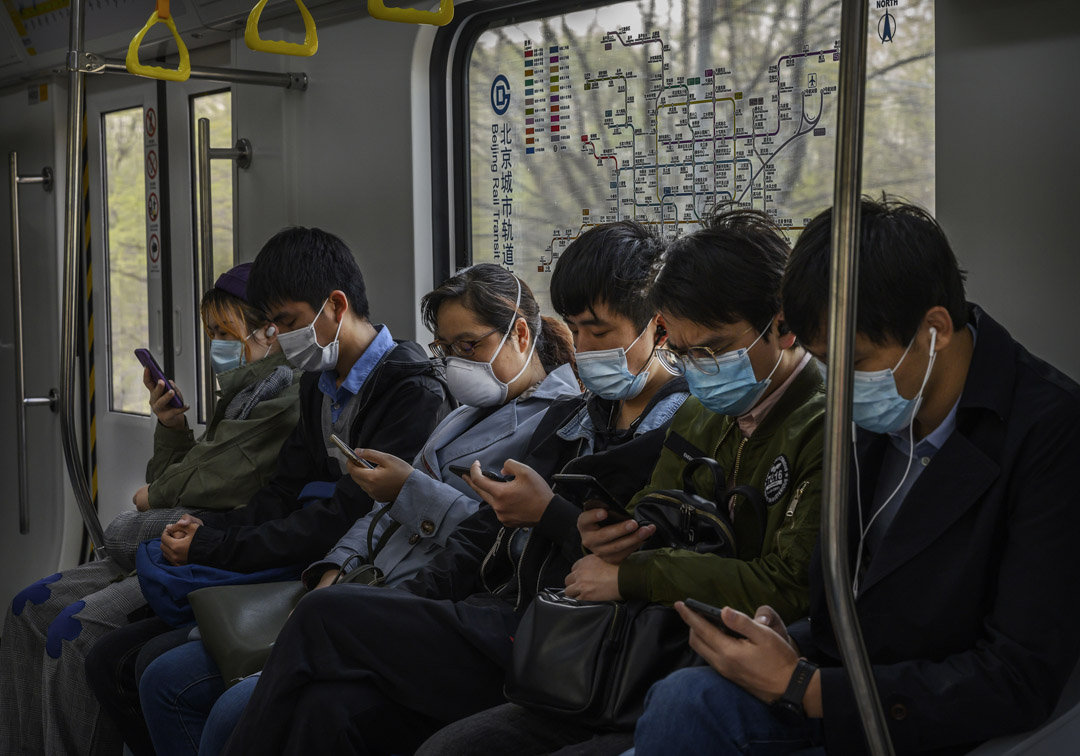 2020年4月15日，北京的高峰繁忙時段，乘坐地鐵的乘客戴著口罩看手機。