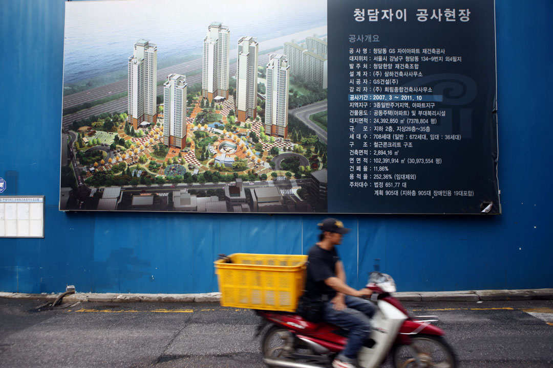 2010年9月3日,一名男子骑着电单车经过韩国首尔一处建筑工地。