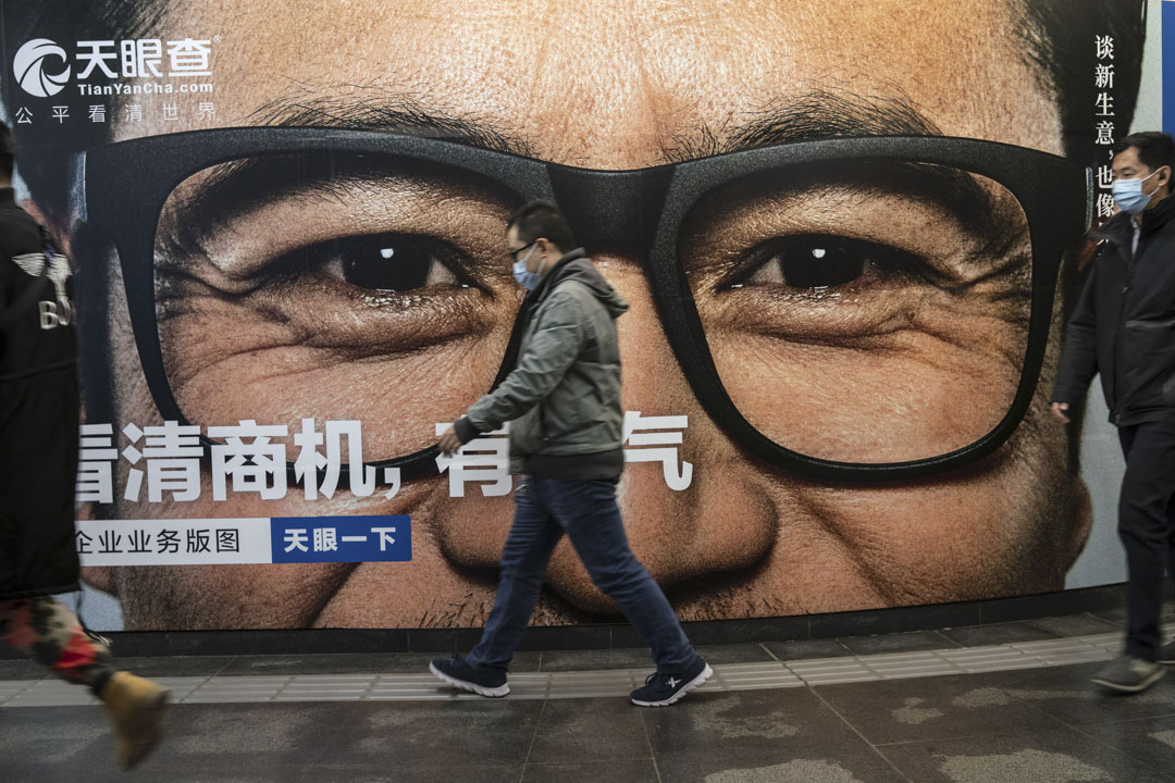 2021年3月3日，戴著口罩的人們走過北京地鐵站的一則廣告。