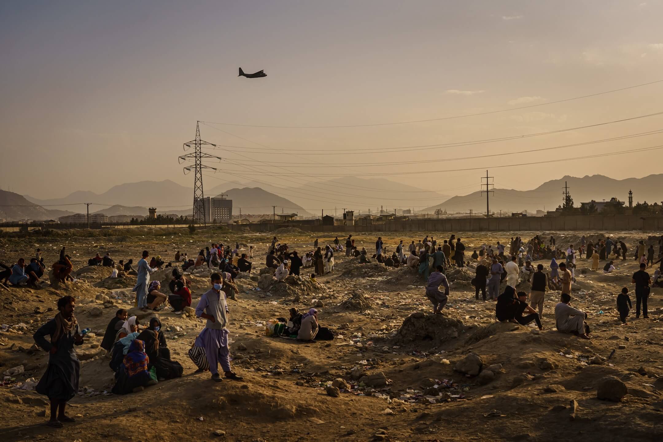 2021年8月23日,阿富汗首都喀布爾,沒有趕及登上美軍軍機的阿富汗人民在機場外聚集,遠處有一輛美軍軍機起飛。