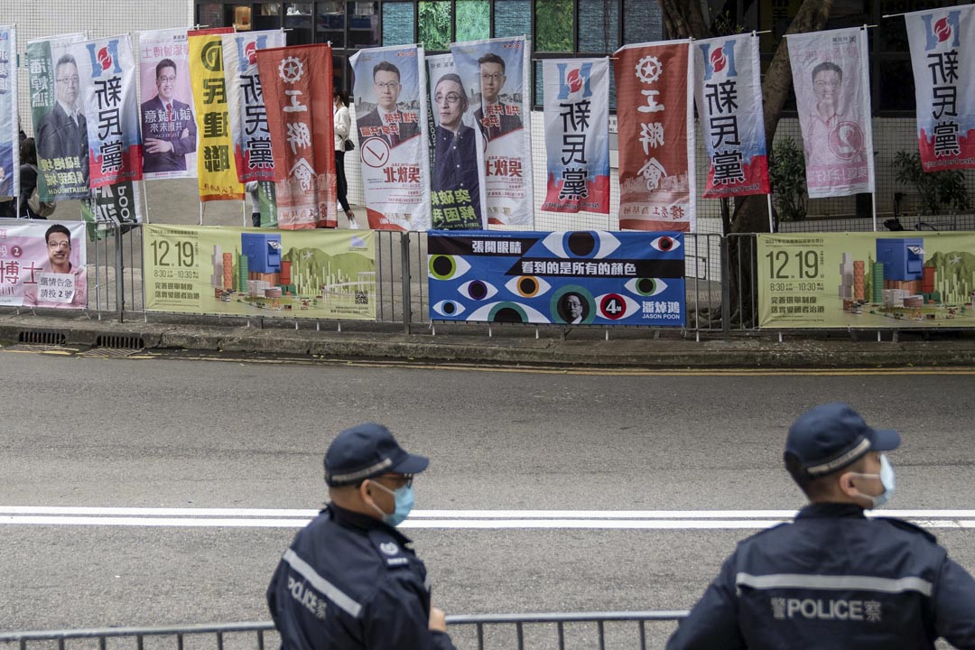 2021年12月19日,港岛东选区,康怡花园马路旁插著多支立法会候选人的旗帜,附近有警员驻守。