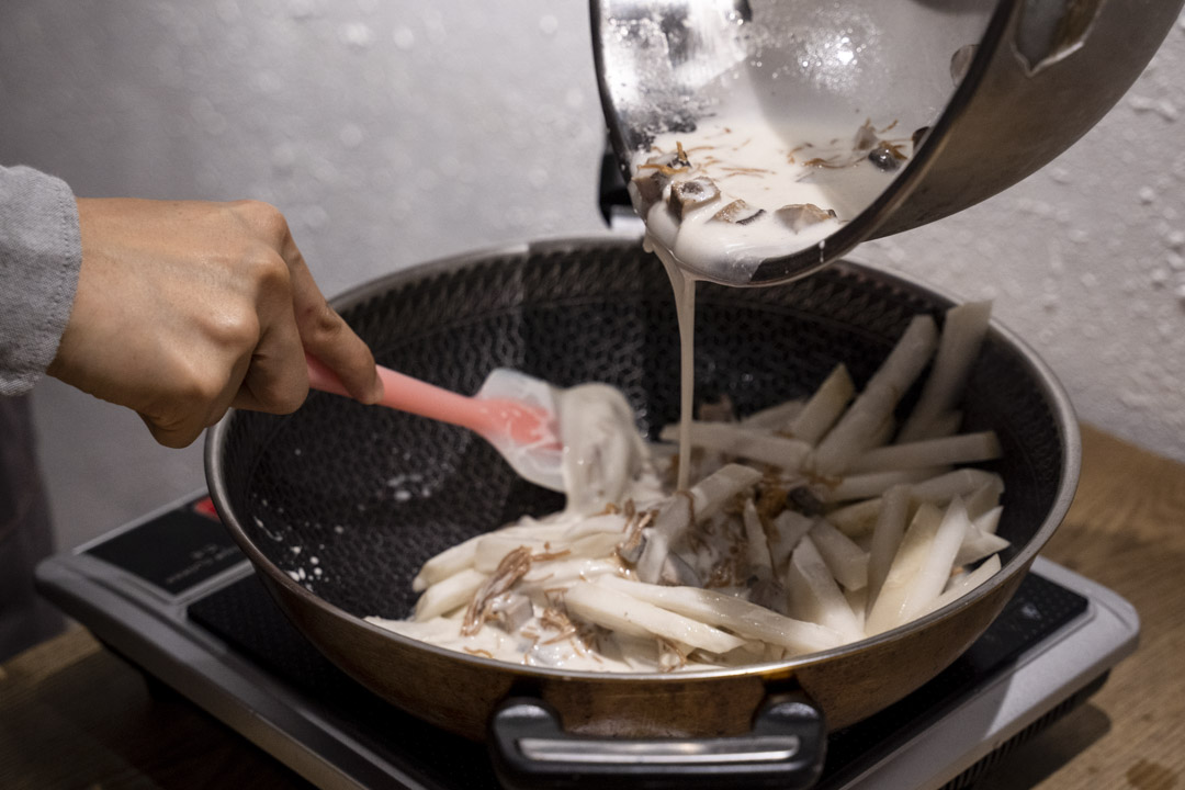 把刚拌好的材料倒入锅中与萝卜撞粉,使萝卜均匀沾上。