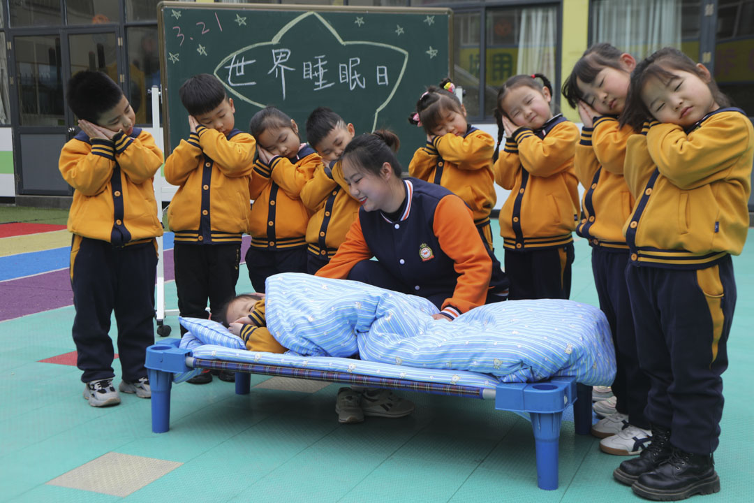 2021年3月18日,河南省洛阳市,一名教师在幼儿园教孩子们正确的睡眠姿势,以迎接世界睡眠日。