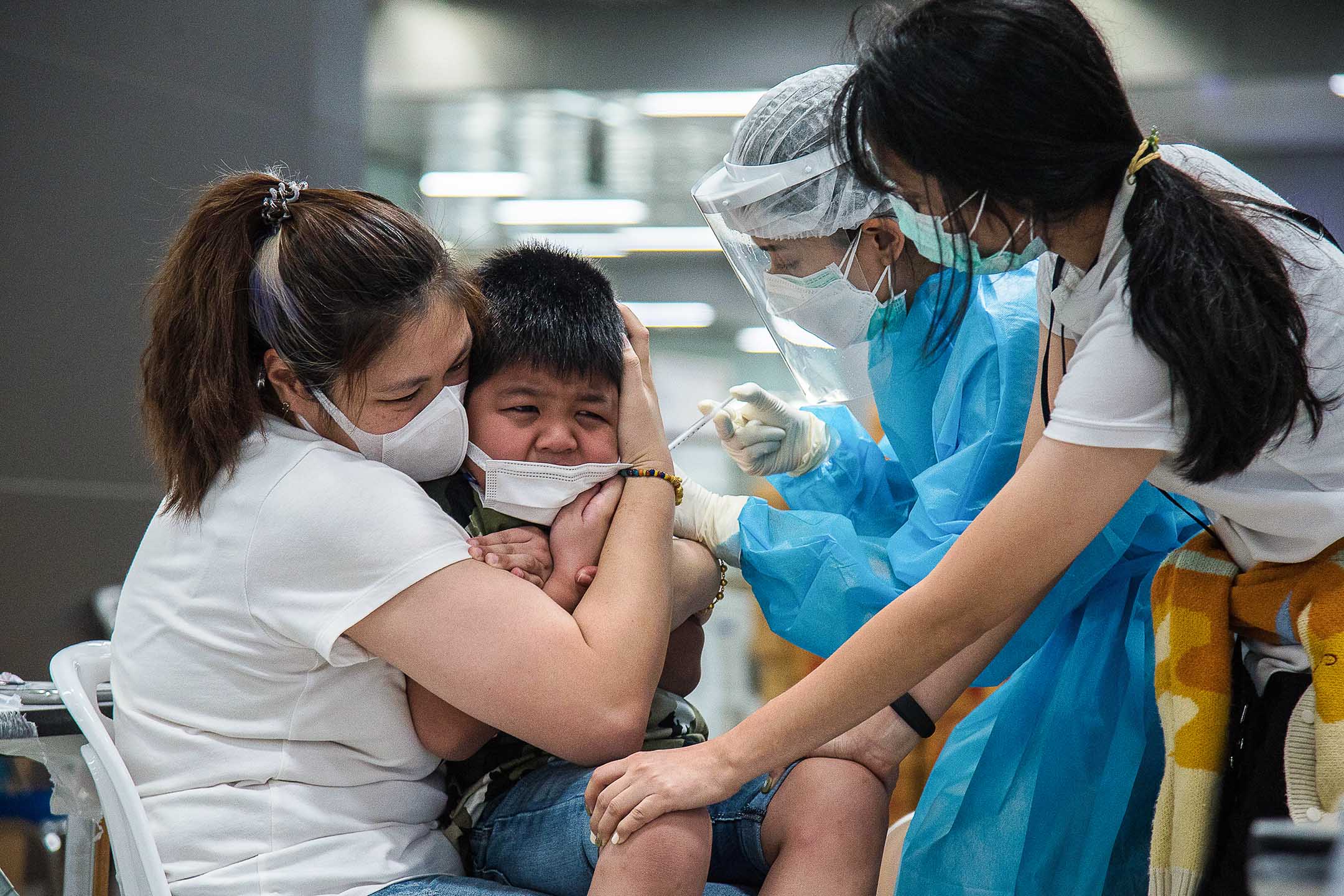 2022年2月20日泰國曼谷，一名醫護人員給一名男孩注射一劑輝瑞疫苗。
