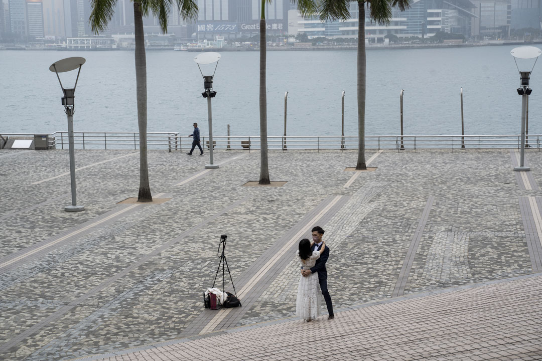 2022年2月13日,尖沙咀一對結婚的新人在空曠的海旁自拍婚紗照。