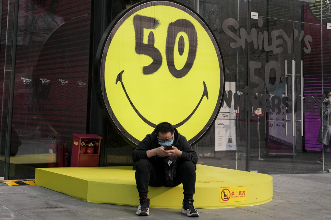 2022年3月10日,北京一名戴著口罩的男子坐在笑臉旁。