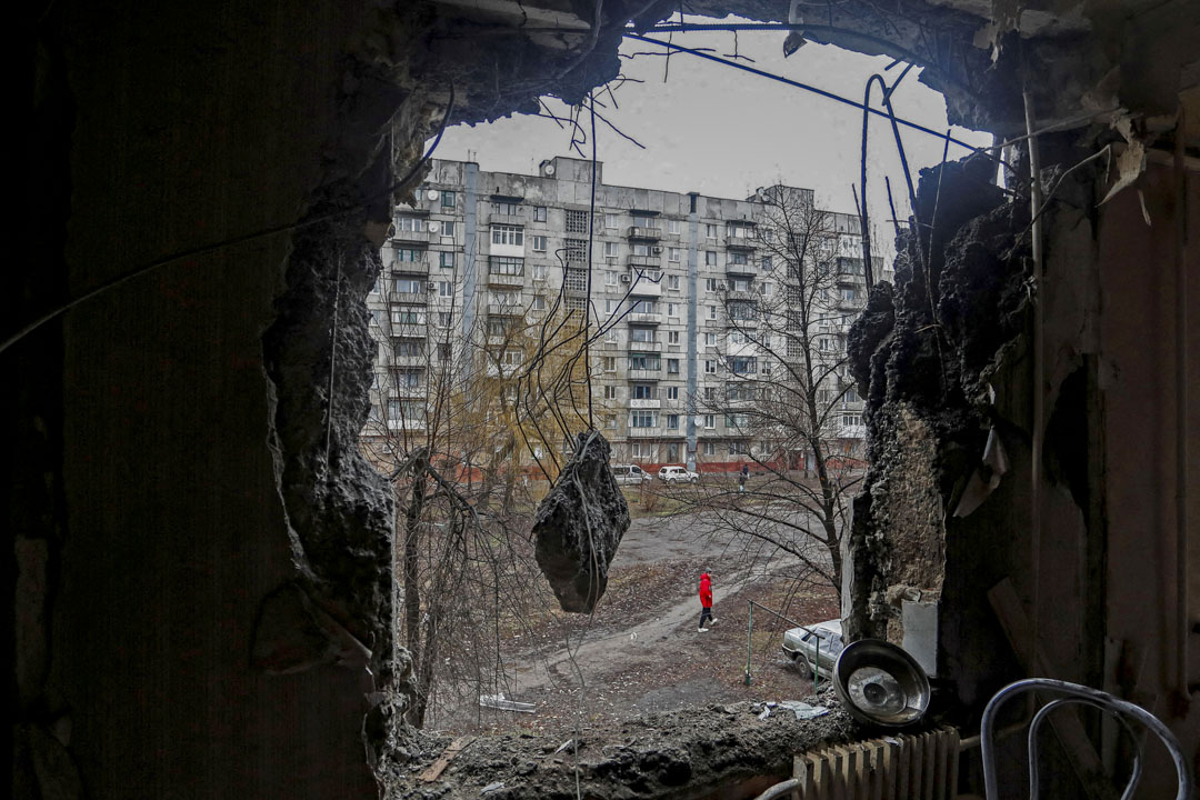 2022年3月2日,乌克兰东部顿涅茨克地区,一座民居的墙壁被炮击炸破,一名男子在大楼外走过。