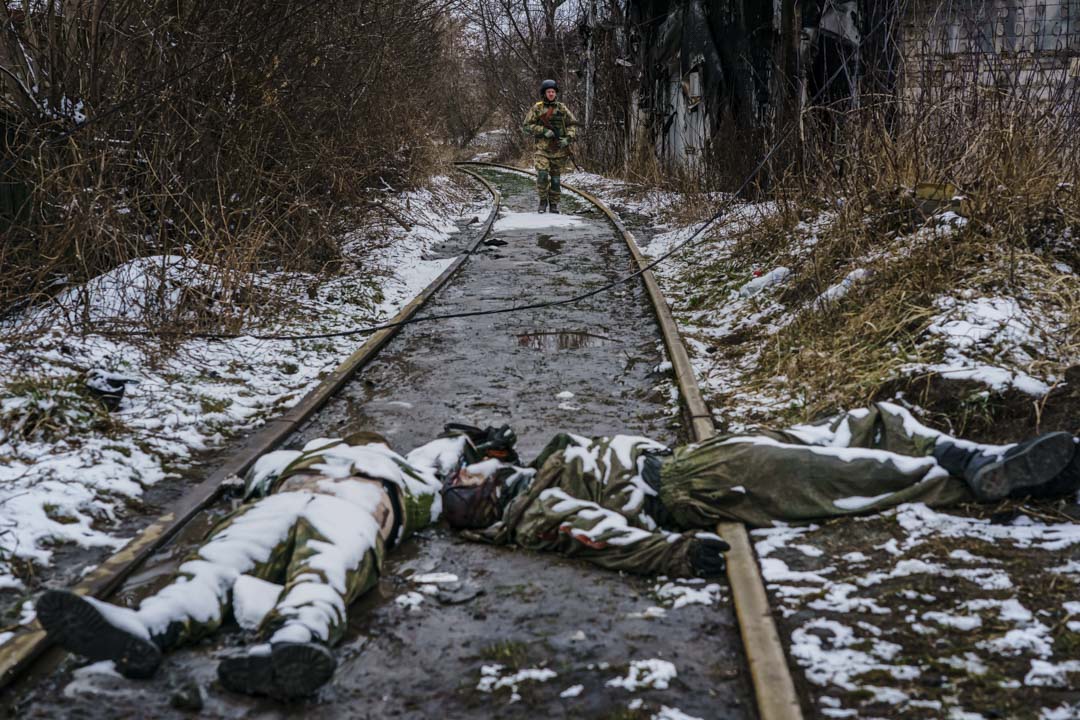 2022年3月1日,烏克蘭伊爾平郊區,一名烏克蘭士兵從鐵路上回來,經過俄羅斯士兵的屍體,在那裡曾與俄軍發生激戰。攝:Marcus Yam / Los Angeles Times