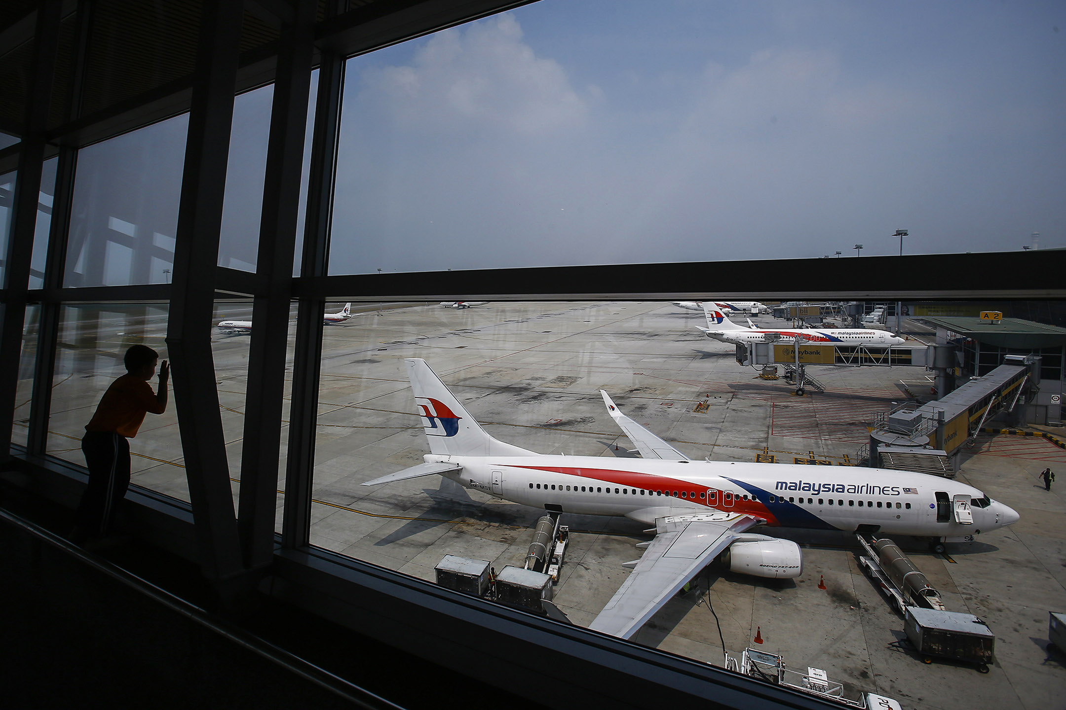 2014年6月27日,一名男孩在吉隆坡國際機場停機坪上看著一架馬來西亞航空公司的波音 737-800 客機。