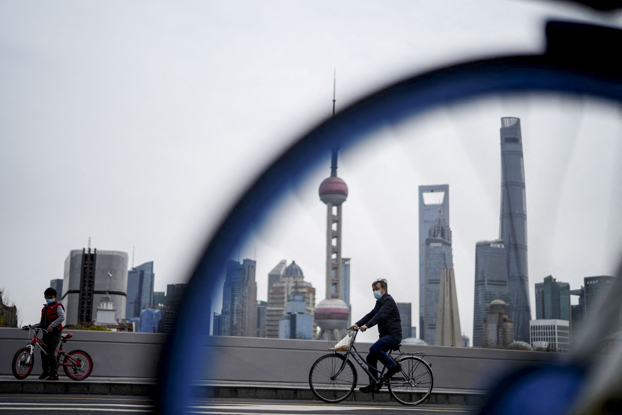 2022年3月28日,上海一名戴著口罩的男子在浦东地区前的一座桥上骑单车。
