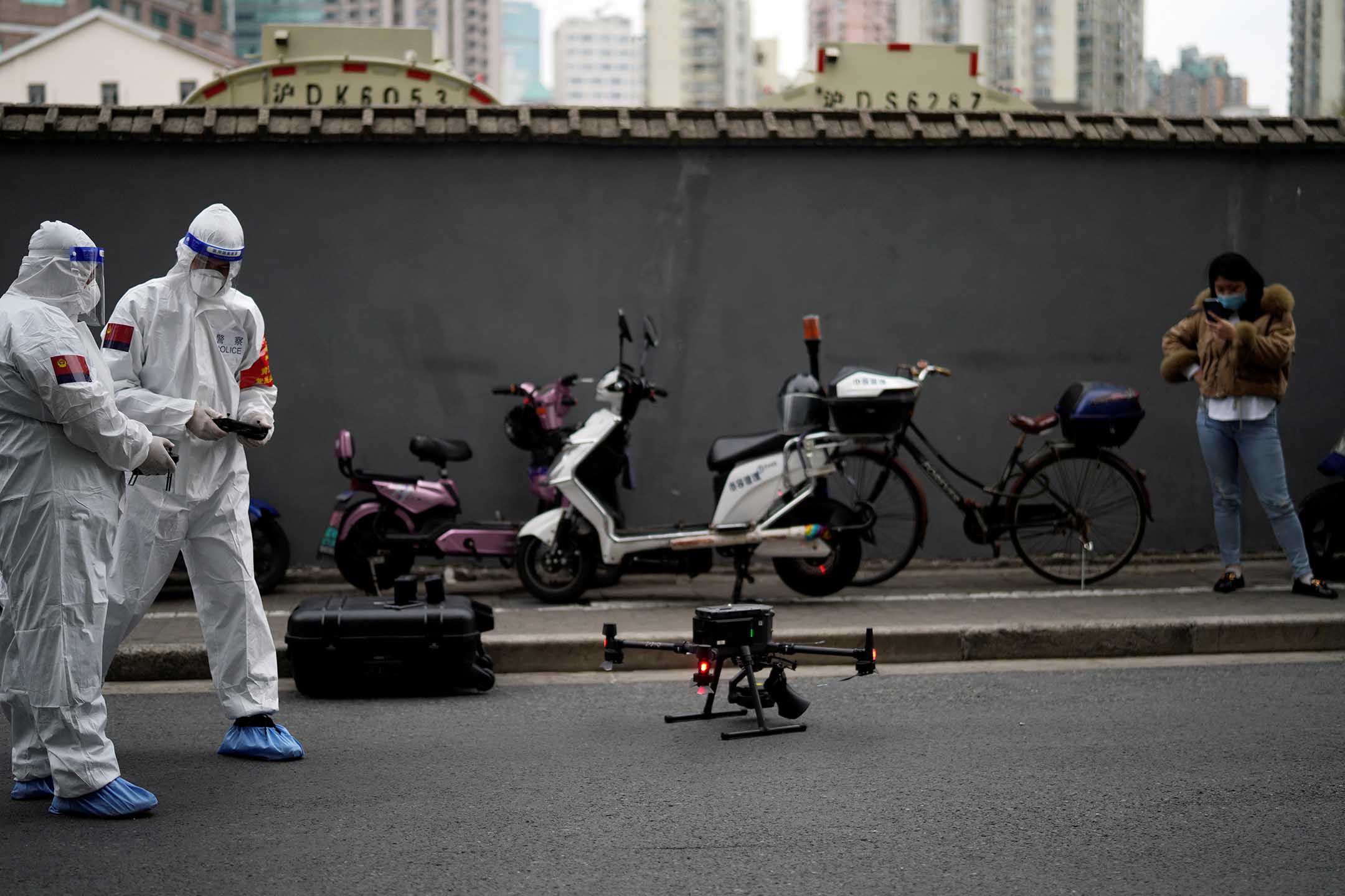 2022年3月30日,上海,身穿防护衣的警察操作一架带有扬声器的无人机,提醒居民采取防疫措施。