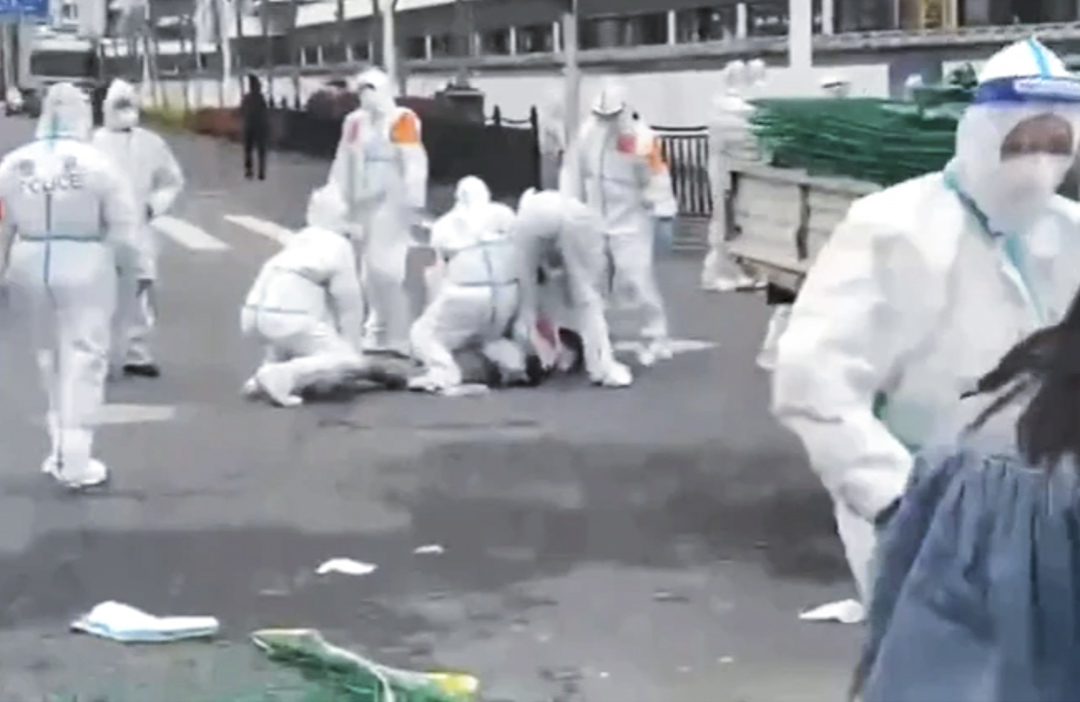 有執行防疫工作的警察將居民壓制在地。