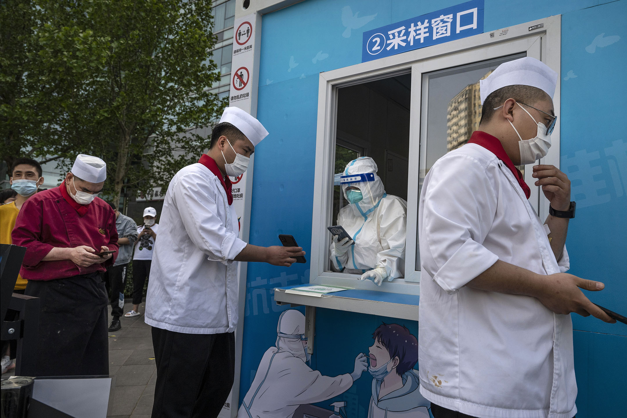 2022年4月26日，北京，一個臨時檢測點，一名工作人員穿著防護服，替排隊的人登記進行核酸檢測。