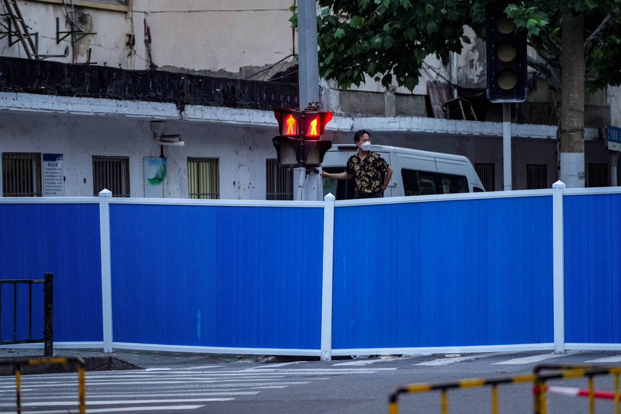 2022年5月16日,上海封城期间,一名男子攀高望向围栏外面。