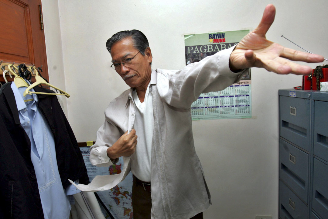 2006年3月9日,在馬尼拉北部奎松市郊區的眾議院接受採訪後,眾議員 Satur Ocampo 穿上襯衫參加會議。