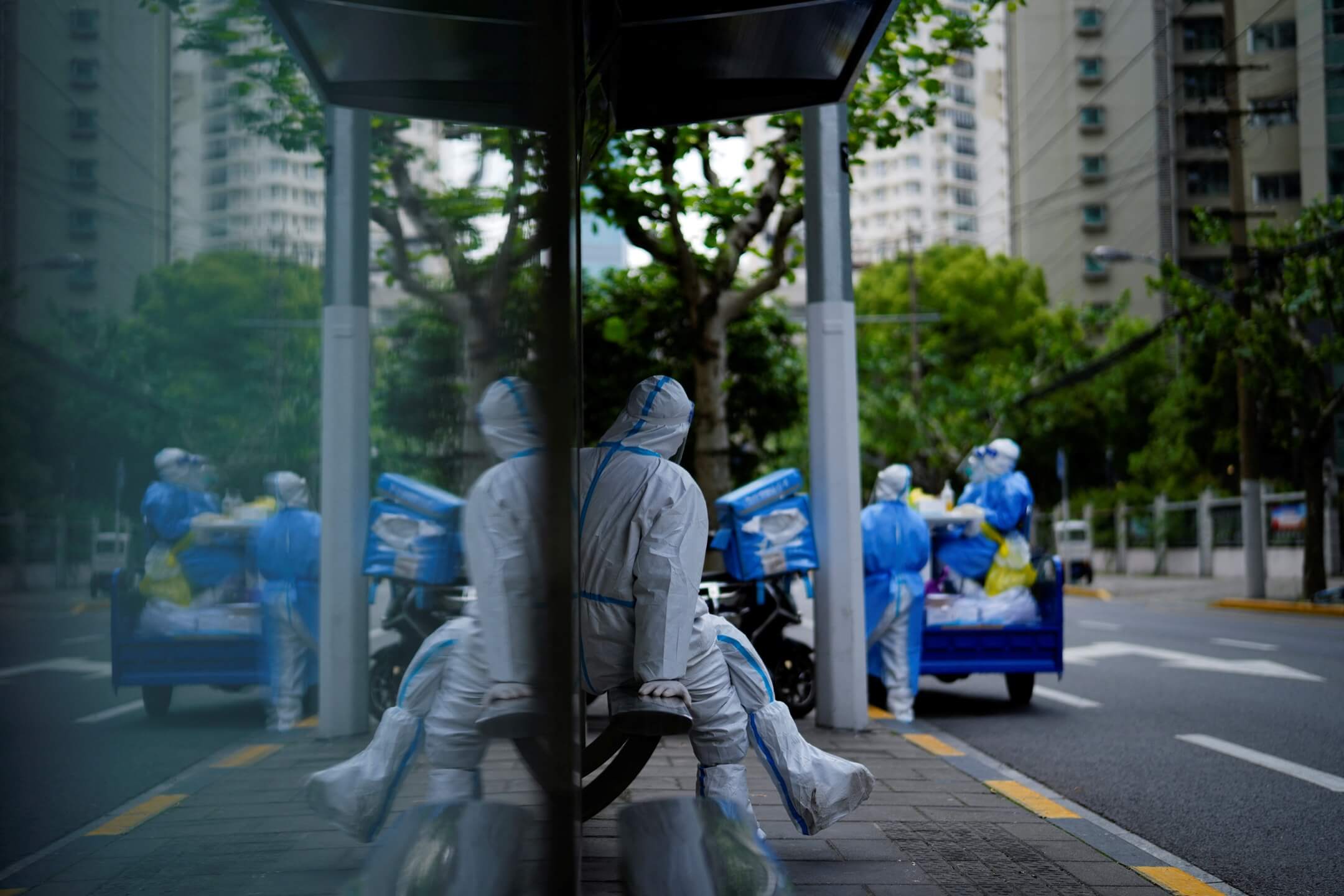 2022年4月30日,中国上海,穿保护衣的工作人员在巴士站整理物资。