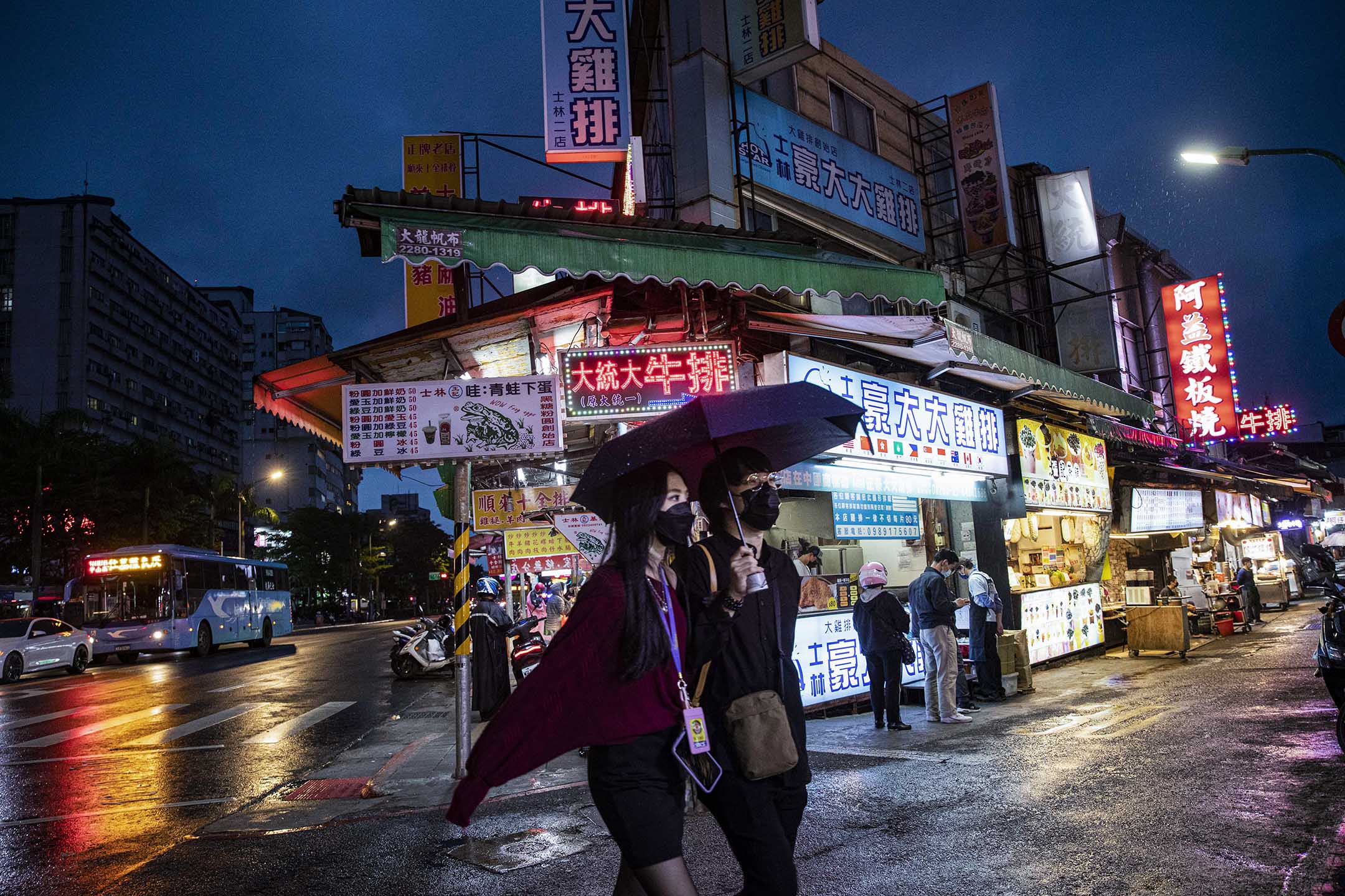 2022年4月21日,台北士林夜市,游人走过夜市上的食店。