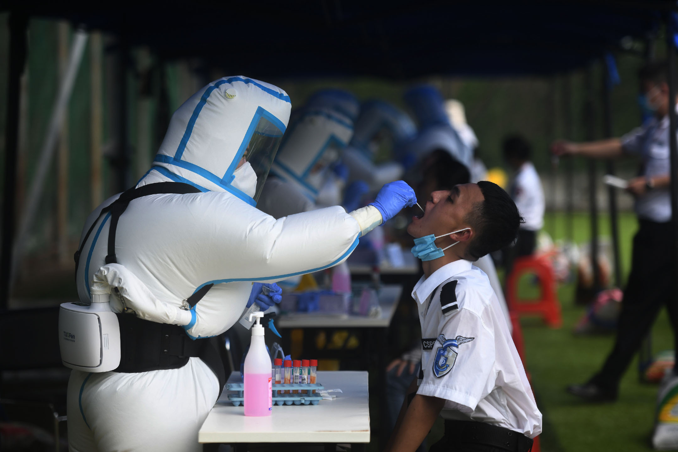2021年8月23日,海南三亞,一名身穿防護服的醫務人員替機場保安人員進行核酸檢測。