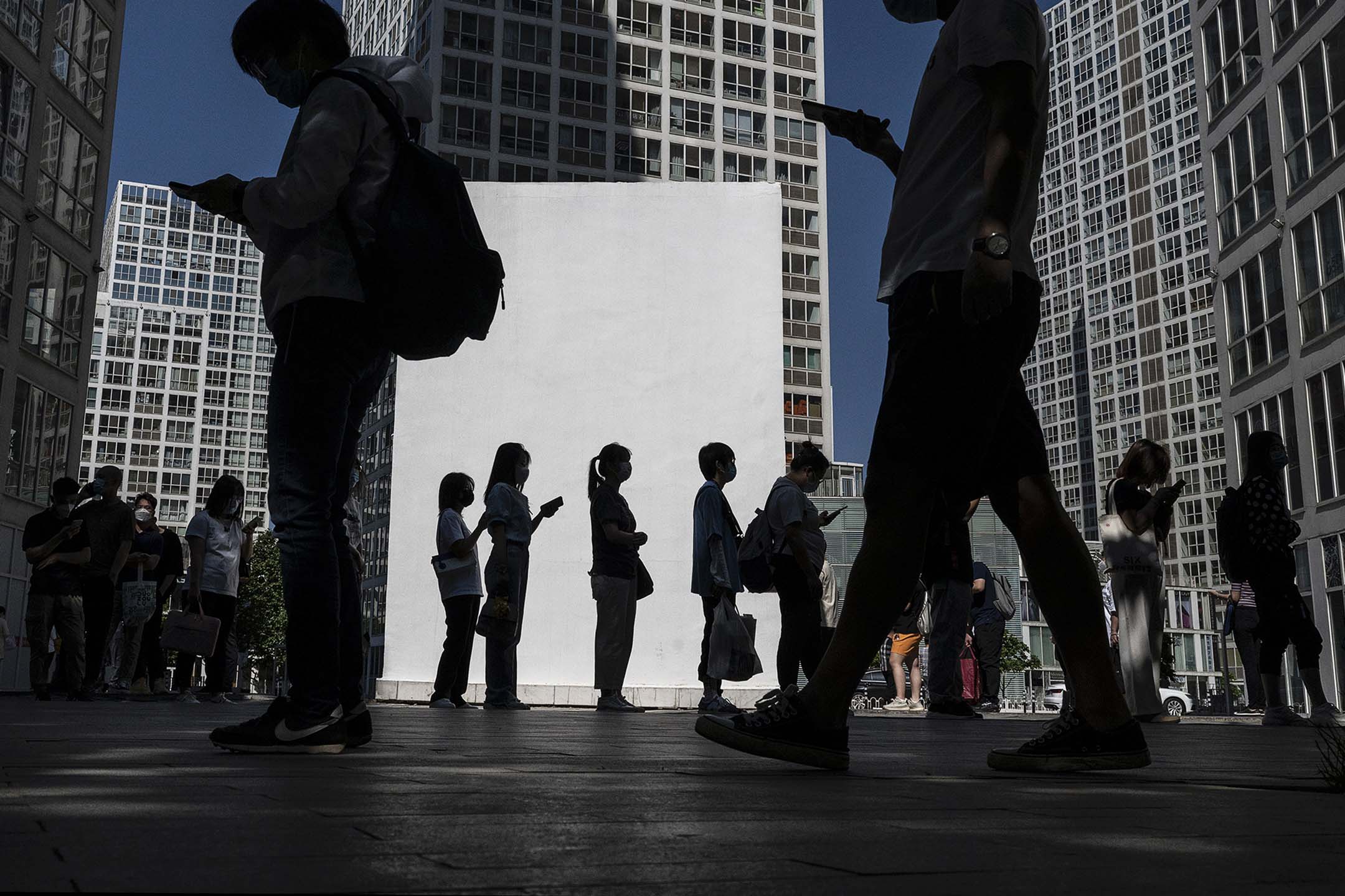 2022年5月30日,北京,复工后办公室职员在办公楼外排队出示健康码和核酸检测阴性证明。