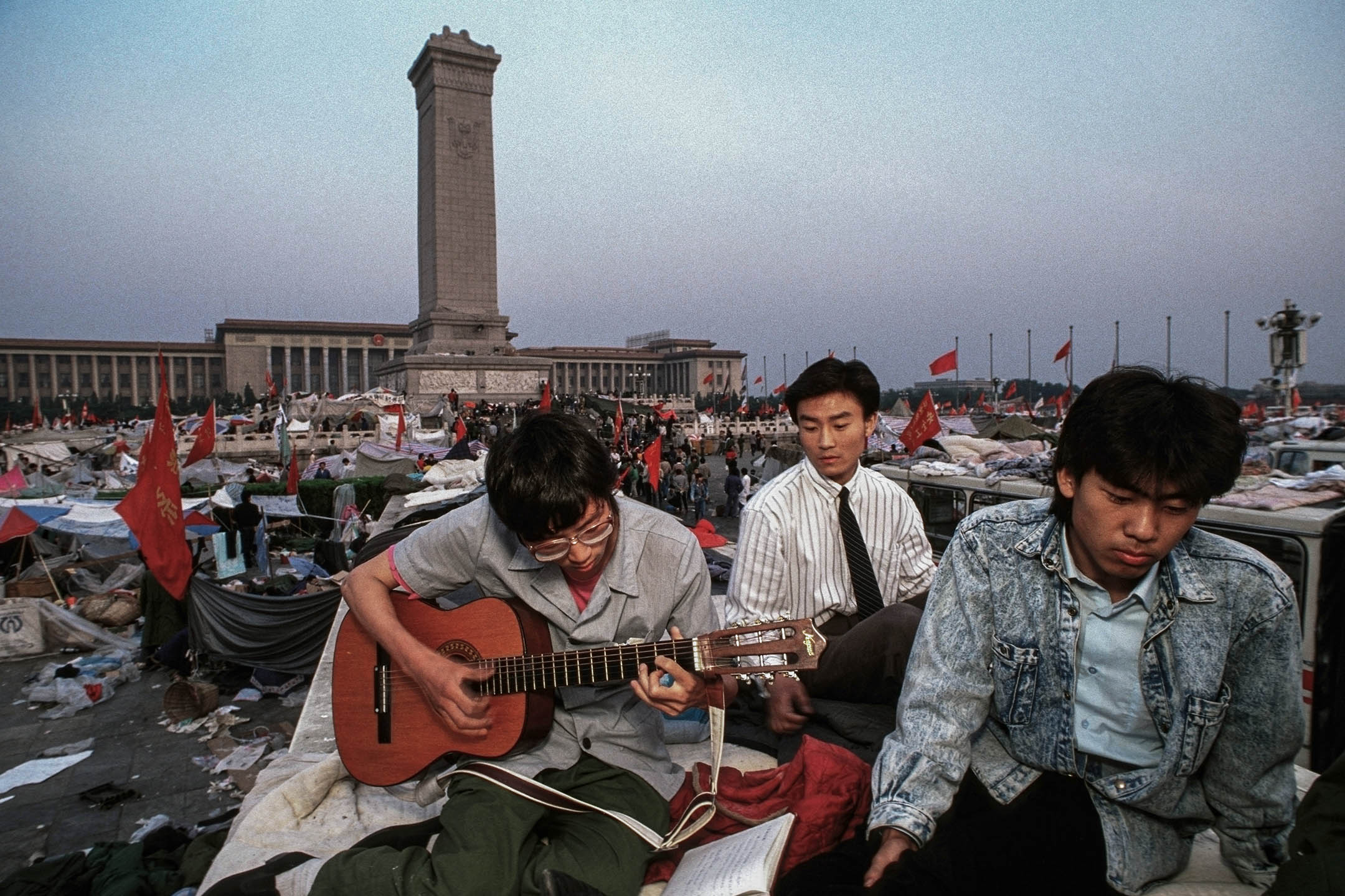 1989年6月1日,北京,一名男子在睡满示威者的天安门广场上弹吉他,以音乐和平抗议。摄:Peter Charlesworth/LightRocket via Getty Images