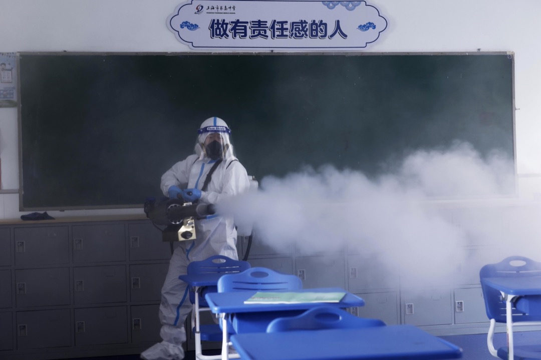2022年4月21日,中國上海,一名防疫人員在一所學校裏噴刷消毒劑。
