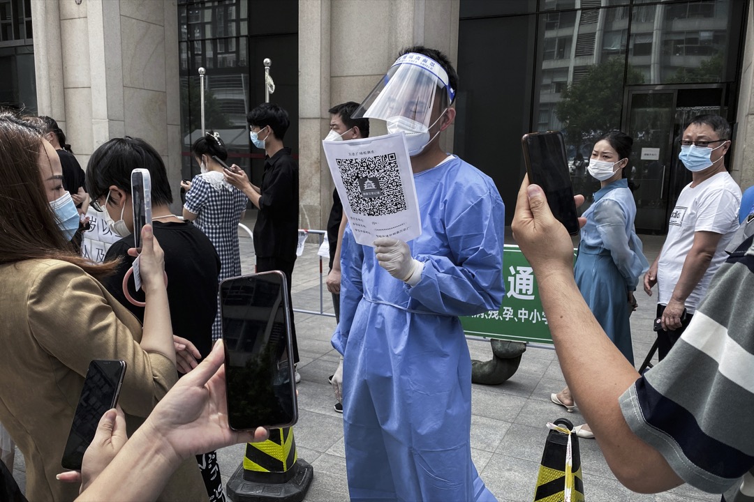 2022年5月,中国首都北京,一名防疫人员举起二维码让公众进入场所前扫瞄。