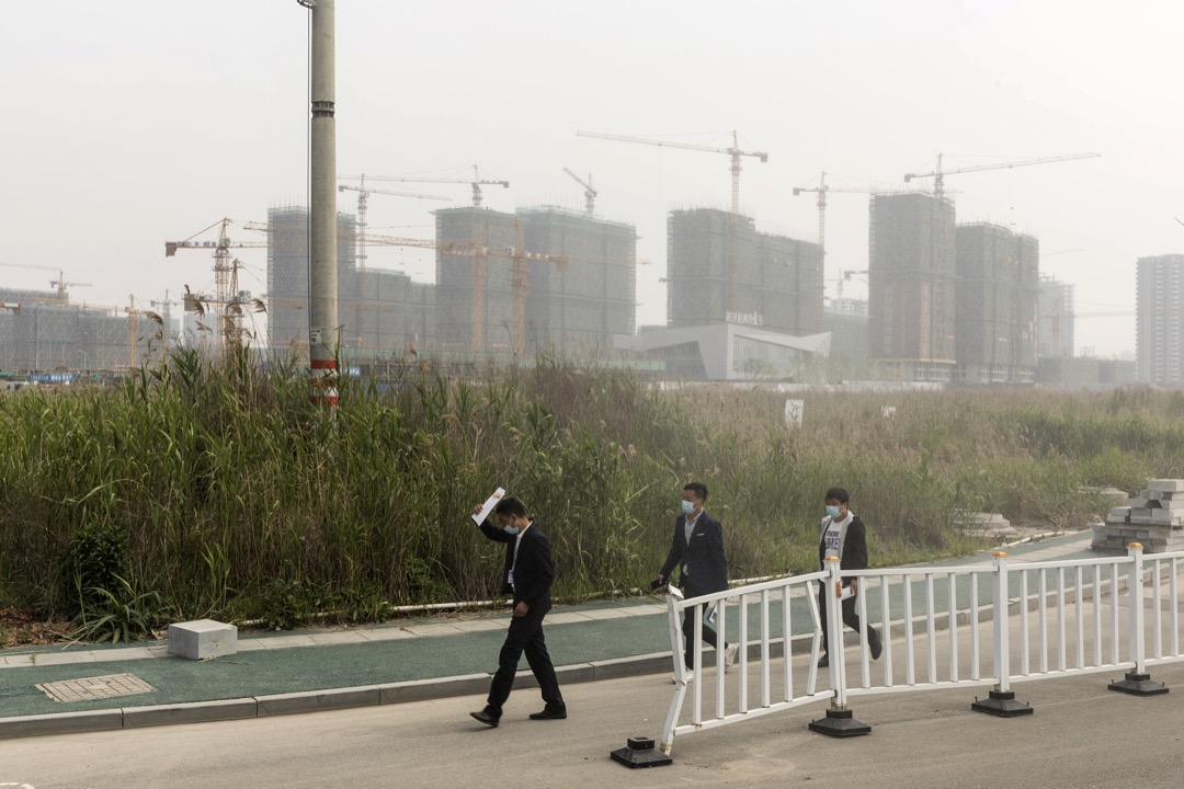 2020年4月，中國寧波市杭州灣新區，三名地產從業員在興建中的住宅前走過。