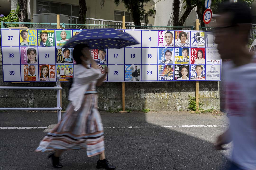 2022年7月10日,东京行人走过一个展示日本参议院选举候选人海报的布告牌。