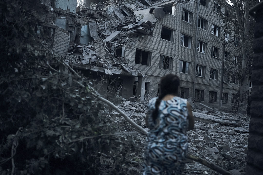 2022年8月2日,烏克蘭 Mykolaiv 發生夜間砲擊後,一名婦女走在住宅樓的廢墟中。