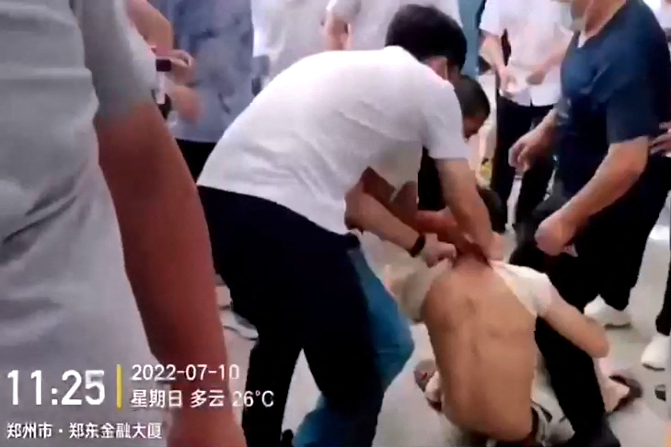 2022年7月10日,河南省郑州的中国人民银行大楼外,村镇银行储户抗议时,安保人员拉著示威者的衬衫将其拖走。