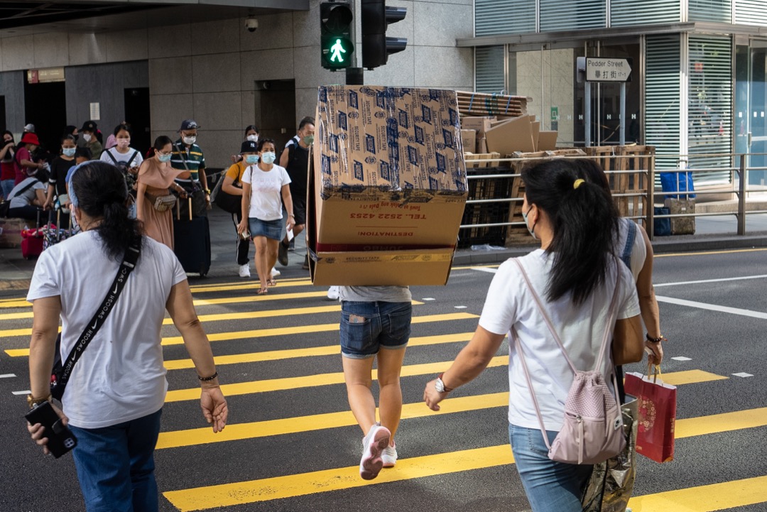 香港,一名移工抬著一個紙箱過馬路。