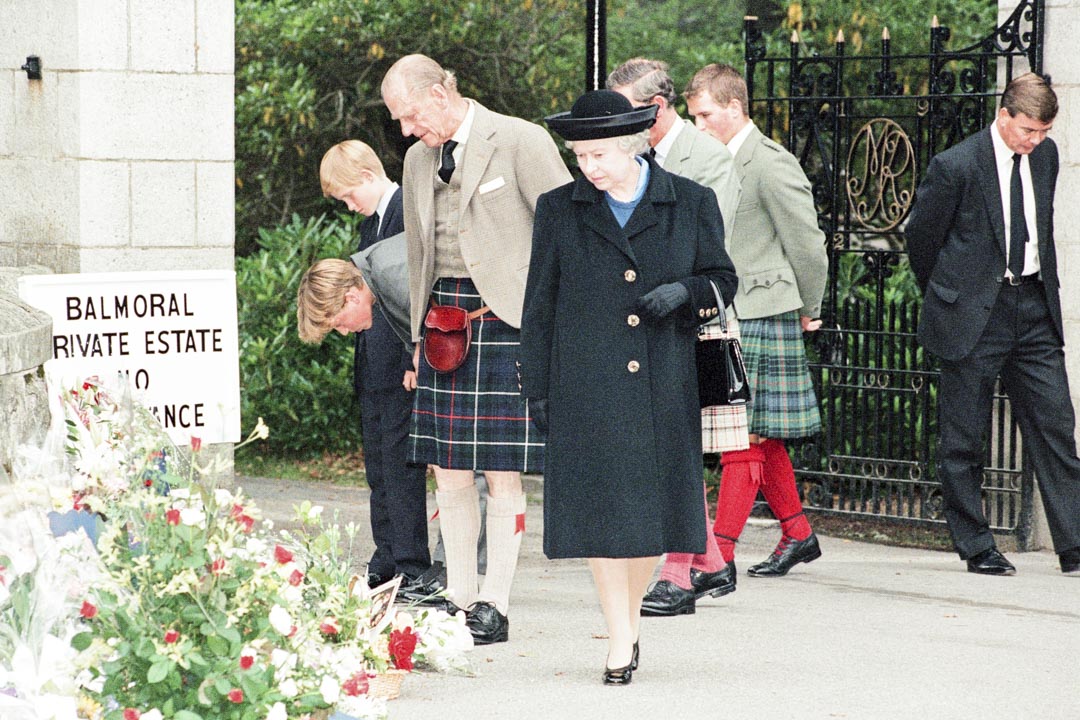 1997年9月5日,苏格兰巴尔莫勒尔庄园,英国王室成员在巴尔莫勒尔城堡的大门前,停下来看民众悼念戴安娜王妃的鲜花。