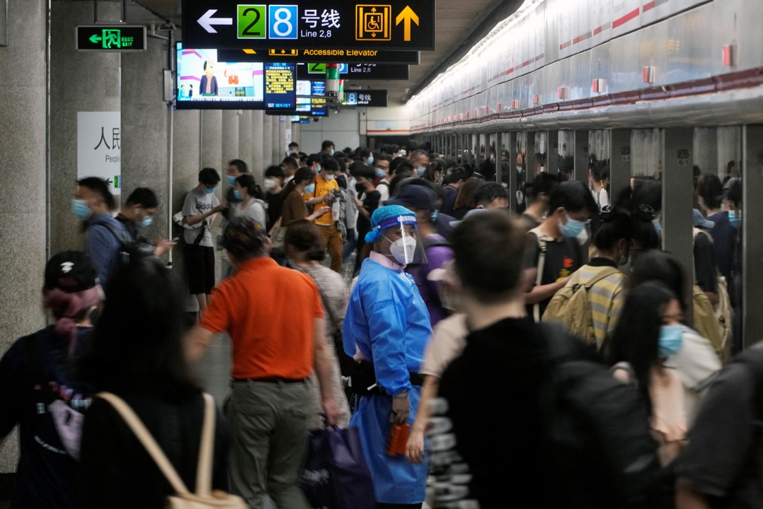 2022年6月1日，中國上海，疫情緩和後，市內解封，一名穿保護衣的工作人員在人來人往的車站看守。