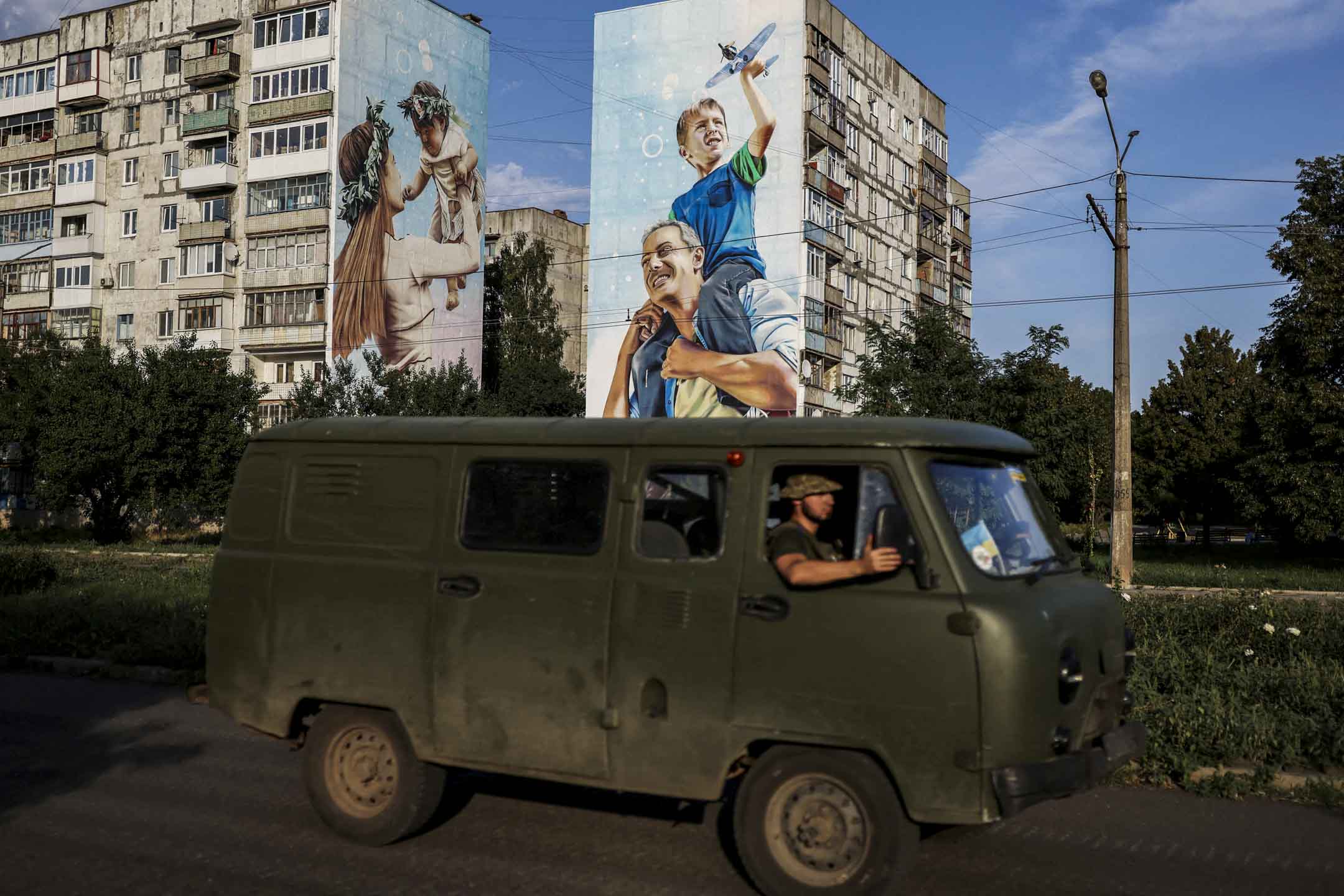 2022年8月14日,烏克蘭頓涅茨克地區,烏克蘭軍人開車經過巴赫穆特受損的建築物。